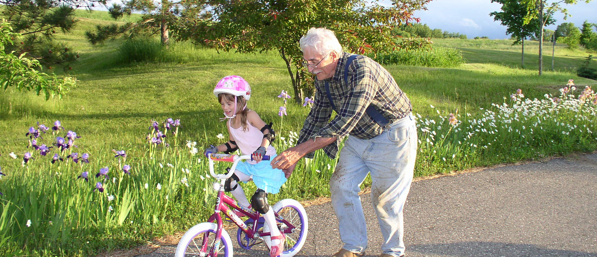 Grandfather teaching granddaughter to ride a bicycle