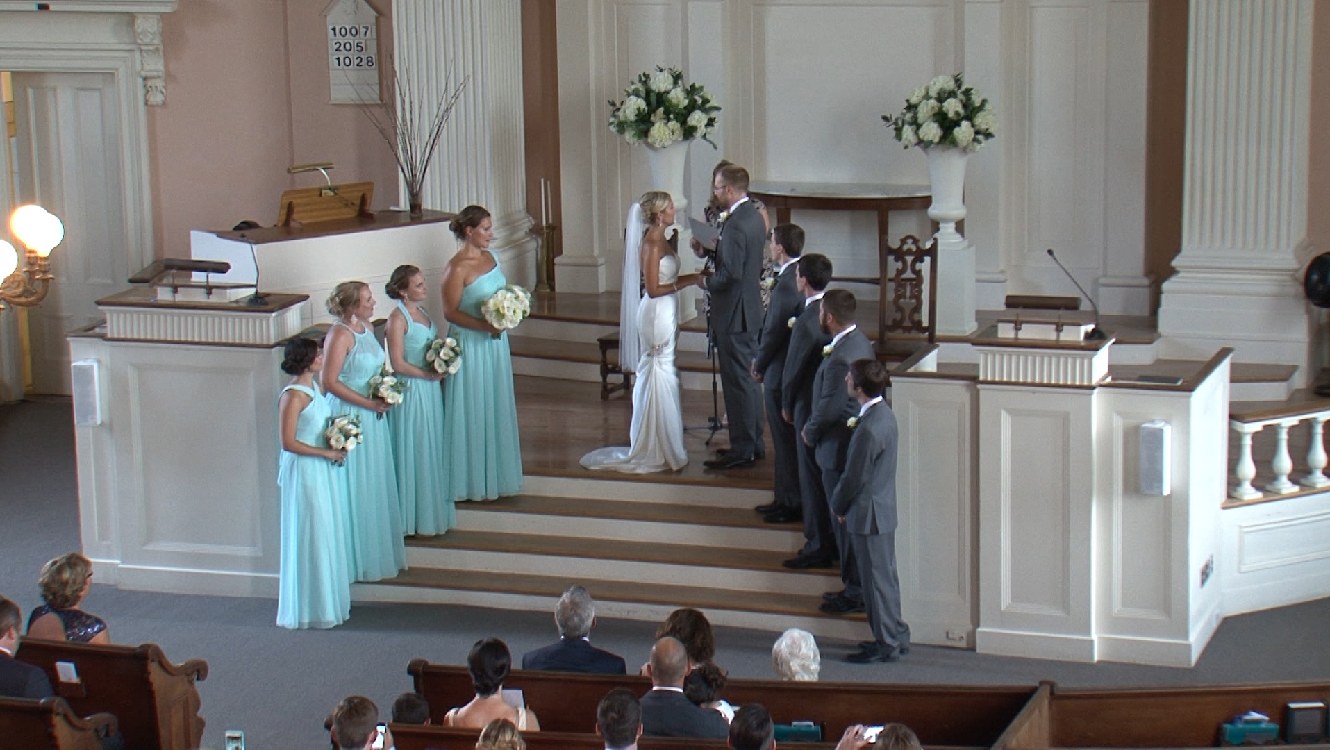 Wedding party on the alter in a still from their wedding video